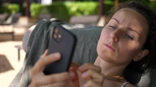 Close Up of Pensive Caucasian Woman Texting on Her Phone While Resting at the Beach