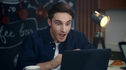 Excited Businessman Reading Good News on Laptop Computer at Home Office.