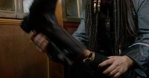 Person Removing Leather Boot in Room