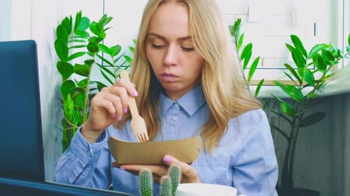 Young Woman Eating Lunch at Desk
