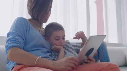 Mother and Child Use Tablet on Couch Together