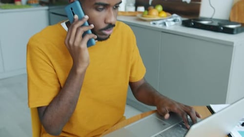 Adult Talking on Phone while Using Laptop at Home