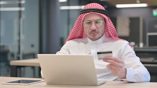 Man Using Laptop and Credit Card in Office