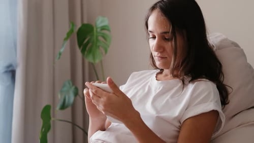 Young Woman Using Smartphone Relaxing Indoors