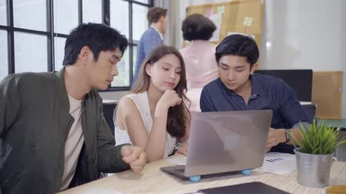 Young Professionals Collaborating on Laptop in Modern Office