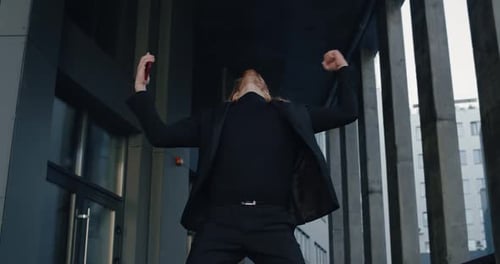 Ausschnittansicht eines aufgeregten Geschäftsmannes, der tanzt und sich freut, während er den Telefoninhalt überprüft. Erfolgreicher Typ