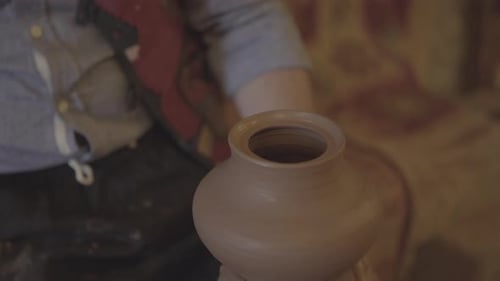Nahaufnahme von Potters Händen, die Ton mit feuchtem Ton auf einer Töpferscheibe bearbeiten und herstellen - 1