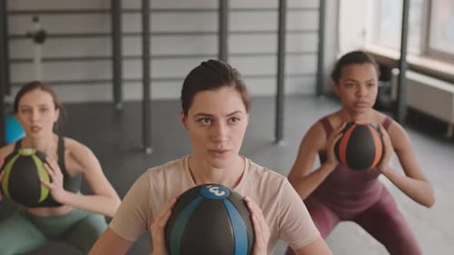 Young Women Performing Squats with Fitness Balls