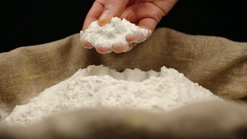 Hand Scoops Flour From Burlap Sack in Close Up