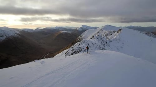 Bergsteiger feiert das Erreichen des Gipfels eines verschneiten Berges