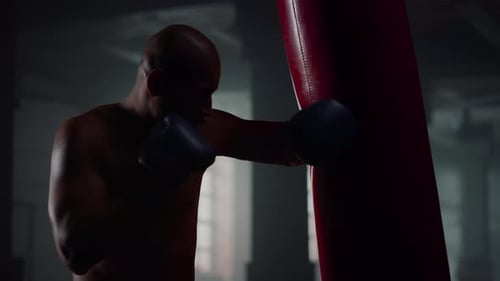 Strong Man Boxing in a Dark Gym