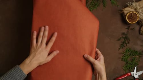 Hands Wrapping Christmas Present with Paper