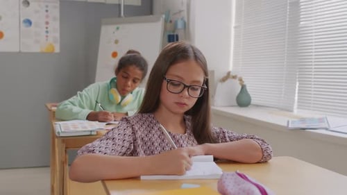 Meninas escrevendo em cadernos durante a aula