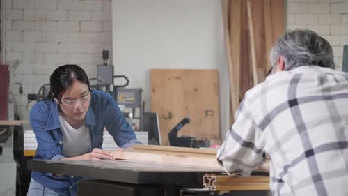 Woman and Man Focused on Woodworking in Workshop