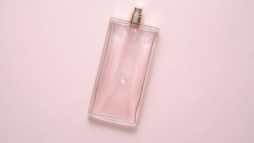 Vue de dessus d'une bouteille de parfum de luxe sur une surface rose pastel. Composition minimale. Lay plat