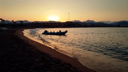 Video of Inflatable Motorboat Floating in Sea Next To the Sandy Beach in Sunset Light