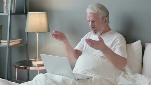 Senior Man Surprised While Using Laptop in Bed