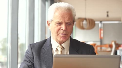 Senior Businessman Drinks Hot Beverage at the Cafe