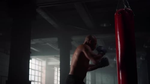 Male Boxer Punching Sports Bag in Sport Club