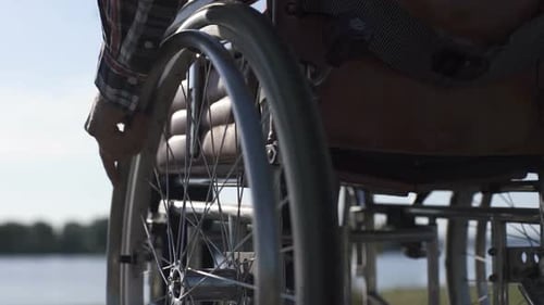 Man Using Wheelchair on Lakeside Path