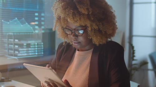 African American Businesswoman Using Tablet in Office at Night