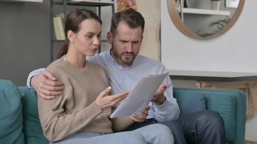 Couple Reviewing Documents Together on Teal Sofa