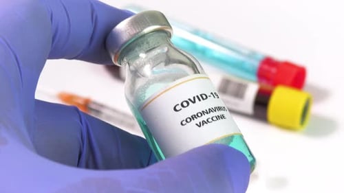 Gloved Hand Holding COVID-19 Coronavirus Vaccine Vial