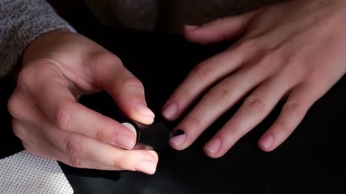 Adult Applies Black Nail Polish in Home Close-Up