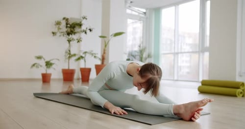 Une belle femme pratique des exercices de spagat dans le studio lumineux Anjaneyasana