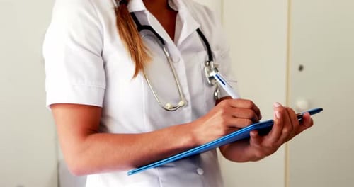 Medical Professional Writing on Clipboard in Hospital Setting