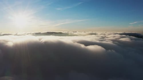 Sonne scheint hell über weißen, flauschigen Wolken bei Sonnenaufgang