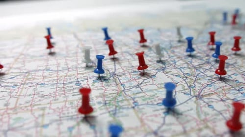 Camera pan revealing red white and blue pins placed marking cities on a US map.