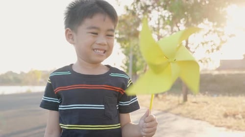 Happiness little boy smiling in wheat field holding small wind wheel or windmill toy