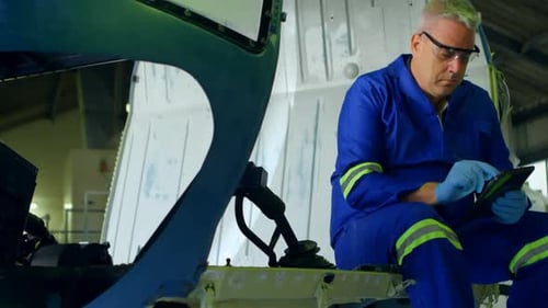 Engineer using digital tablet at aerospace hangar 4k