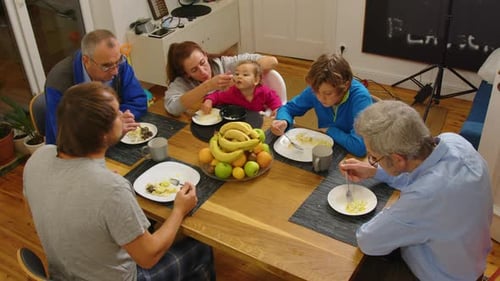 High Angle View of Large Multigenerational Family Sitting Together at Table Putting Food on Plates