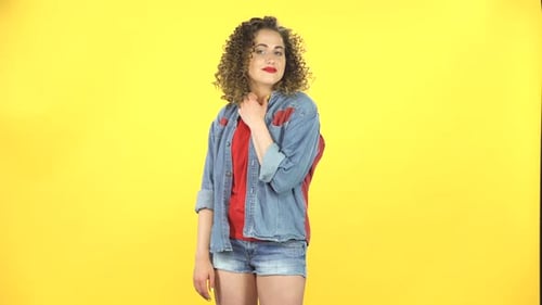 Chica rizada sonríe coquetamente mientras mira a la cámara, construye sus ojos, de manera seductora