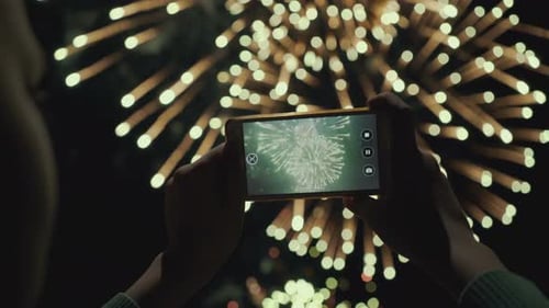 Person Records Fireworks with Smartphone at Night