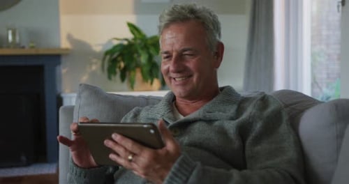 Smiling Man Using Tablet on Sofa Indoors