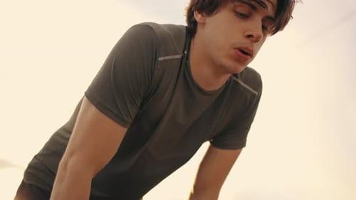 Exhausted Young Male Athlete After Jog or Training Outdoors Portrait of Man Against Sky