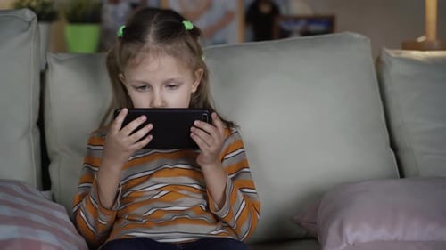 Girl Concentrating on Phone While Sitting on Sofa