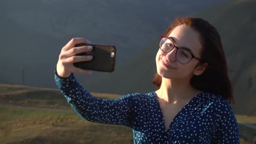 Young Woman Takes Selfie in Front of Mountains