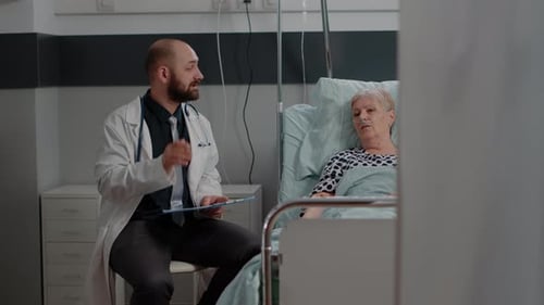 Doctor Consults with Senior Woman in Hospital Bed