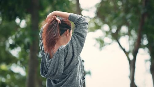 Young asian sport woman tie hair making ponytail ready to exercise in public park