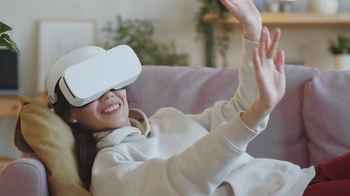 Woman Smiling, Interacting with Virtual Reality Headset on Couch