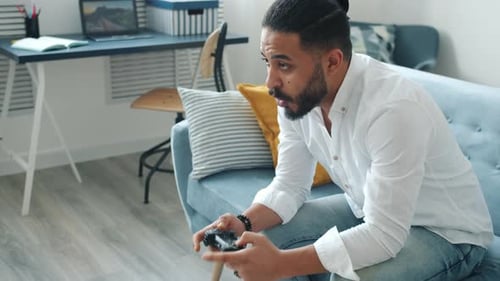 Man Playing Video Game on Sofa at Home