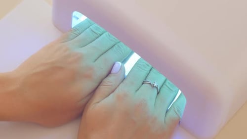 Woman Curing Nails Under LED Lamp
