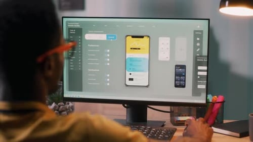Hombre negro creando una aplicación de teléfono móvil en la computadora