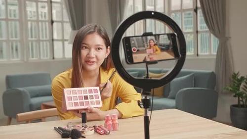 Mujer bloguera de belleza asiática filmando un tutorial diario de rutina de maquillaje en un teléfono inteligente