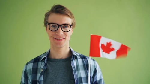 Smiling Man Holding Small Canadian Flag Indoors