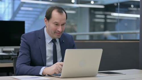 Businessman Talking on Video Call on Laptop in Office